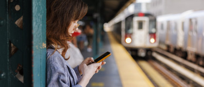 Woman checking her phone on an elevated subway platform